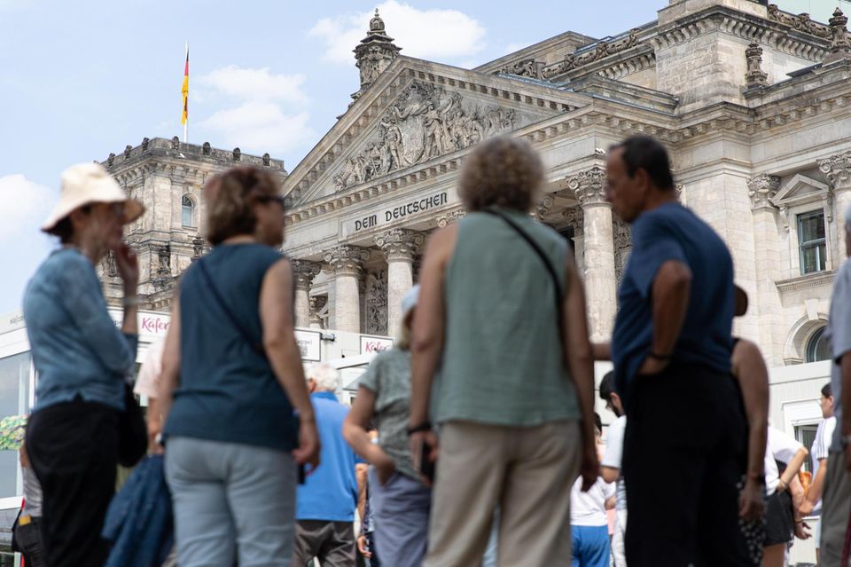 Vor dem Reichstagsgebäude in Berlin stehen Touristen