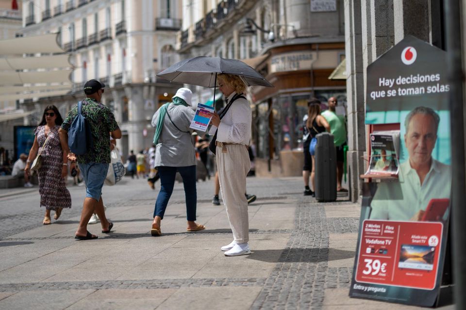 Eine Frau schützt sich mit einem Schirm vor der Hitze