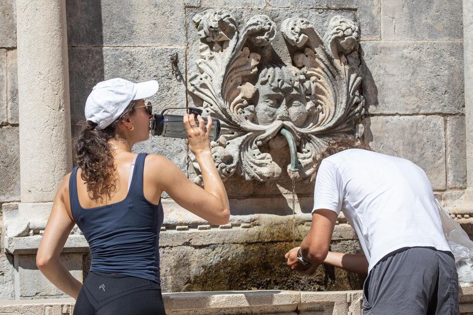 Menschen kühlen sich an einem Brunnen ab