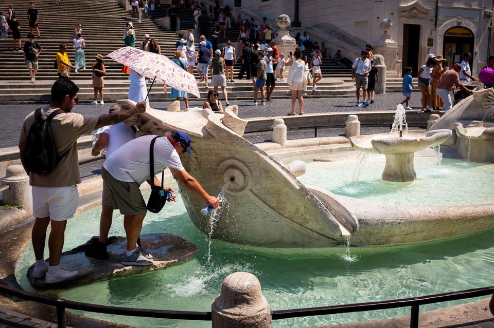 Touristen kühlen sich an einem Brunnen in Rom ab