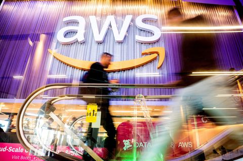 Ein Mann steigt auf eine Rolltreppe, im Hintergrund ist das Logo von AWS zu sehen