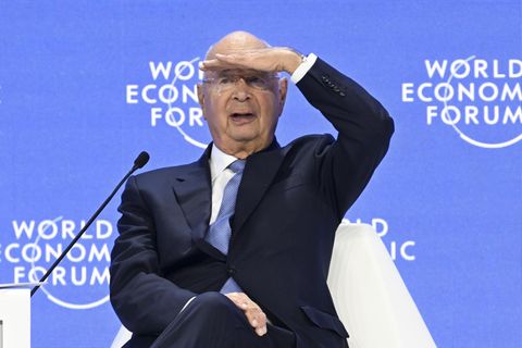 Klaus Schwab sitzt auf einem Podium des Weltwirtschaftsforums und sieht ins Publikum