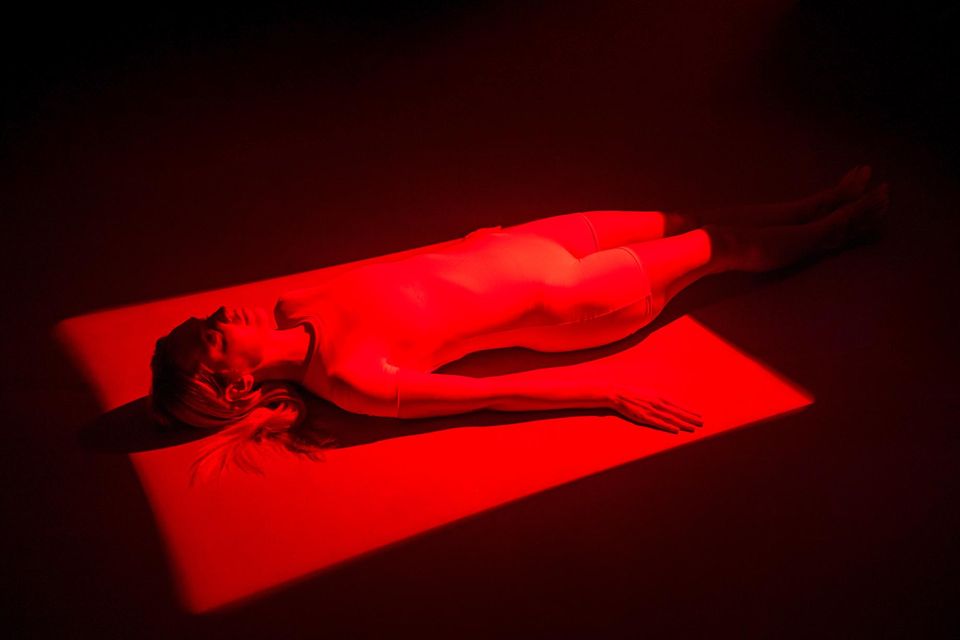 A woman bathed in red light lies on a lounger