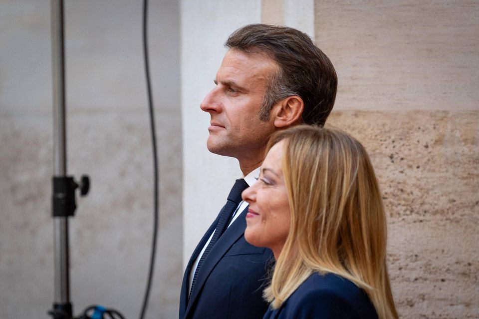 El presidente francés, Macron, y el primer ministro italiano, Meloni, se saludan.