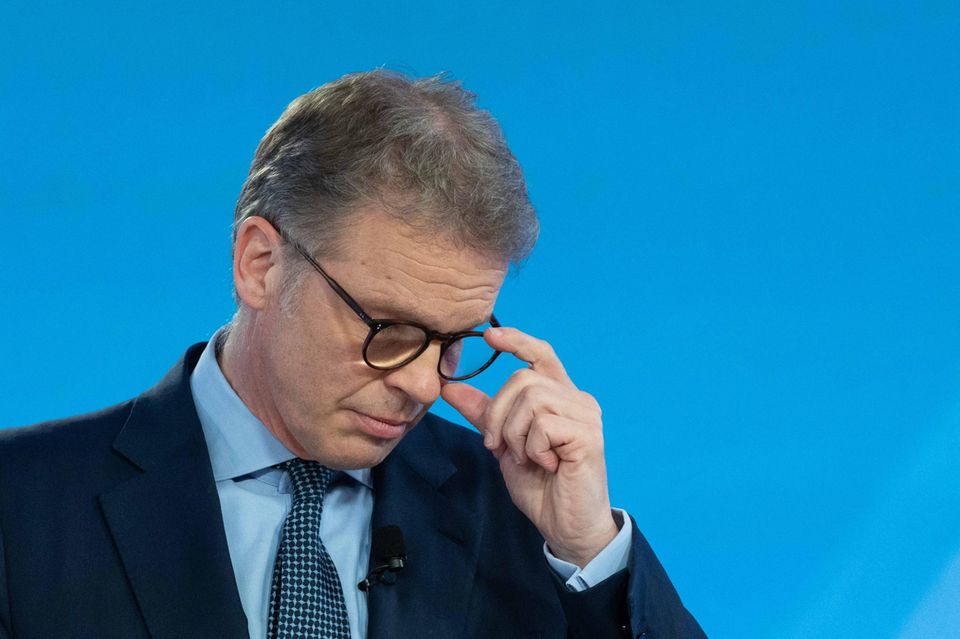Christian Sewing steht auf einer Bühne und richtet die Brille