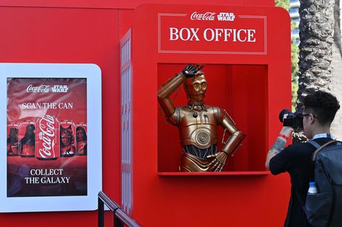KI: Star Wars-Droidencharakter C-3PO an einem Coca-Cola-Stand zum Thema Star Wars