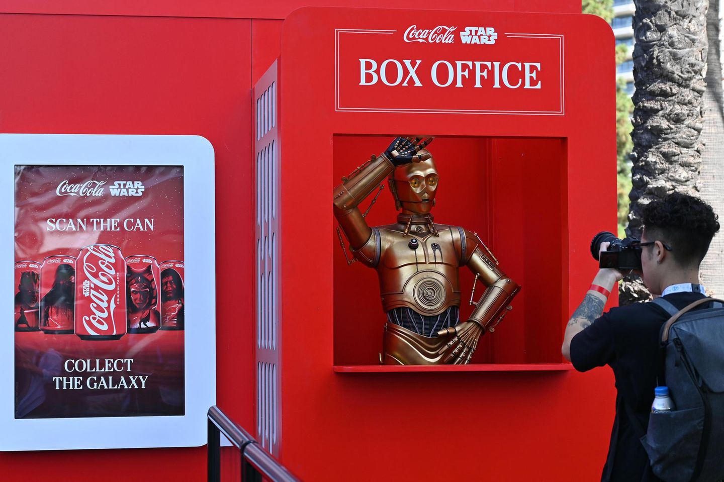 KI: Star Wars-Droidencharakter C-3PO an einem Coca-Cola-Stand zum Thema Star Wars