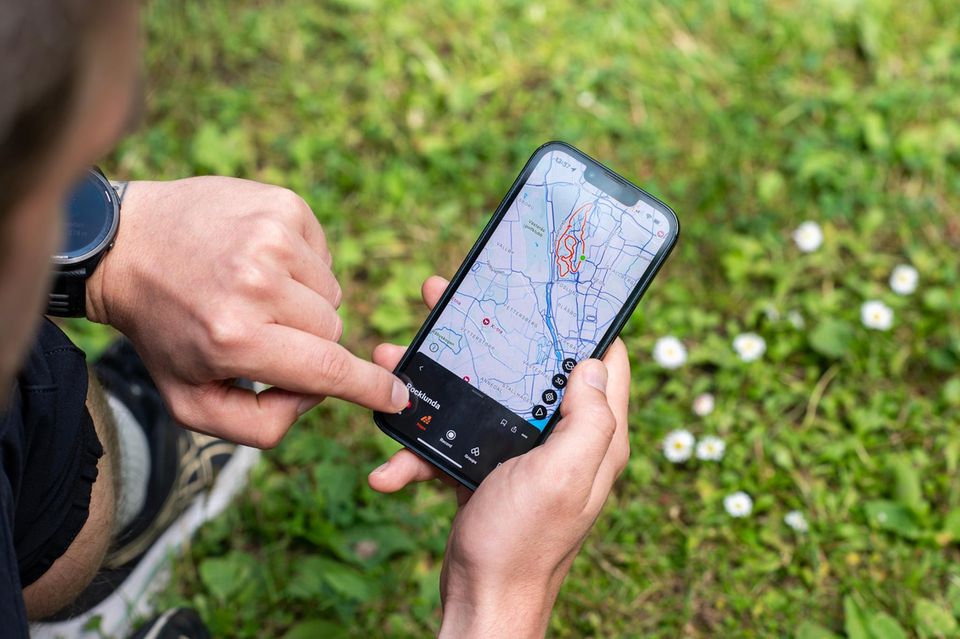 Ein Läufer hat die Fitnessapp Strava auf dem Smartphone geöffnet
