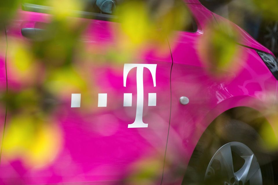 Magentafarbenes Fahrzeug der deutschen Telekom mit Firmenlogo hinter einer Hecke