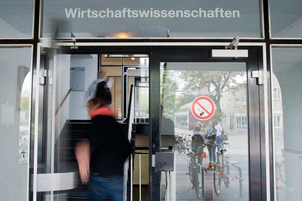 Studierende betreten eine Tür, über der Wirtschaftswissenschaften steht