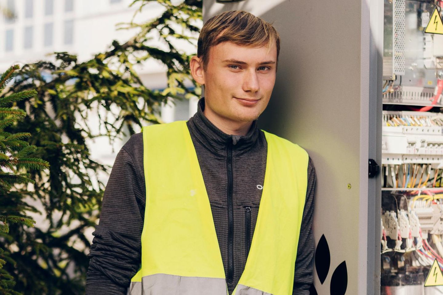 Ian Behring lehnt mit einer gelben Weste gegen einen Schaltkasten