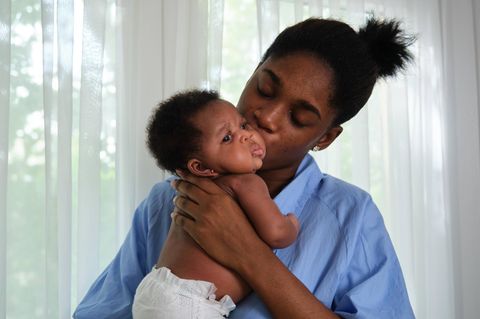 Eine junge Mutter küsst ihr Baby Eine junge Mutter küsst ihr Baby