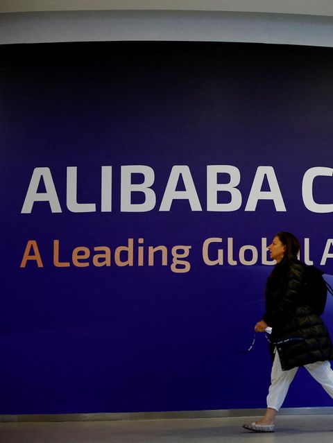 Menschen gehen beim Mobile World Congress 2025 an einem Alibaba Cloud-Schild vorbei.