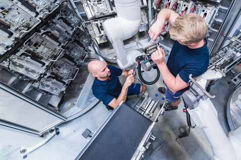 Zwei Männer arbeiten an einem Roboterarm