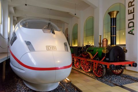 Ein moderner ICE steht neben der Nachbildung einer Adler-Lokomotive im Museum